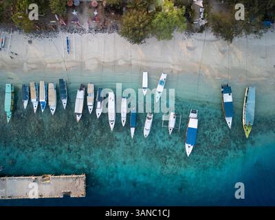 Vue aérienne de la belle plage tropicale avec eau turquoise claire et voiliers ancrés, Pemenang, Indonésie. Banque D'Images