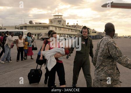 14 janv. 2010 - Port-au-Prince, Haïti - le second maître de 2e classe de la Garde côtière américaine DANIEL WILBURN, technicien en maintenance aéronautique, guide le personnel américain affecté par le séisme de magnitude 7,0 jusqu'à un avion HC-130 Hercules en attente. Le personnel de la Garde côtière a travaillé pour évacuer près de 140 membres du personnel américain d'Haïti. (Crédit image : © Mariana O'Leary/US Coast Guard/ZUMApress.com) Banque D'Images