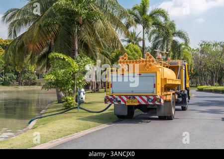 Bangkok, Thaïlande - 25 mars 2017 : jardinier ouvrier non identifié du parc public travaillant pour l'arrosage des plantes de pelouse et des arbres par camion-citerne d'eau Banque D'Images