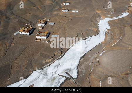 Vue aérienne d'une petite colonie de maisons le long d'un ruisseau gelé avec quelques champs agricoles près de Kaza township, Himachal Pradesh, Inde. Banque D'Images