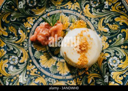 Un dessert avec une fraise sur le dessus et une sauce sur le côté. Le dessert est sur une assiette avec une bordure jaune Banque D'Images