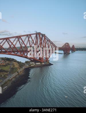 Vue aérienne du majestueux pont Forth enjambant la voie navigable tranquille au coucher du soleil, North Queensferry, Royaume-Uni. Banque D'Images