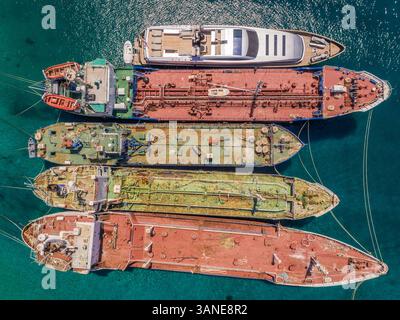 Vue aérienne d'un yacht de luxe amarré avec de vieux bateaux cargo dans la mer méditerranée, Nisi, Grèce. Banque D'Images