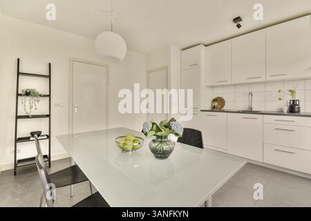 Une cuisine épurée et minimaliste avec une table à manger, un éclairage élégant et une touche de verdure, mettant en valeur l'esthétique contemporaine du design d'intérieur. Banque D'Images