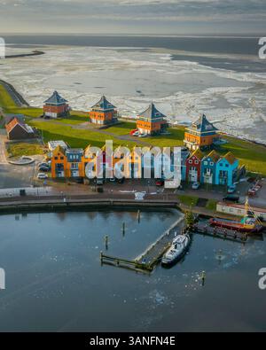 Vue aérienne d'un village pittoresque avec des maisons colorées et un port gelé au coucher du soleil, Stavoren, pays-Bas. Banque D'Images