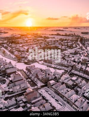 Vue aérienne d'un village pittoresque couvert de neige au lever du soleil, Makkum, pays-Bas. Banque D'Images