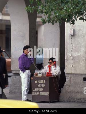 04 juil. 1998 - Cuenca, Azuay, Équateur - les hommes parlent au téléphone. Les caractéristiques dominantes de la géographie de la ville sont également à l'origine de son nom : les quatre rivières de Cuenca, Tomebamba, Yanuncay, Tarqui et Machangara. Ces quatre rivières font partie du bassin versant de l'Amazone. Cuenca (qui signifie un bassin causé par un confluent de rivières) est entouré de montagnes de tous les côtés, avec des cols à l'ouest, au sud et à l'est. (Crédit image : © Ricardo J. Ferro/ZUMA Press) Banque D'Images