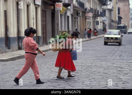 04 juil. 1998 - Cuenca, Azuay, Équateur - Une femme se fait faire briller ses chaussures dans le parc par un enfant pendant qu'un homme lit le papier sur le banc à côté d'elle. Les caractéristiques dominantes de la géographie de la ville sont également à l'origine de son nom : les quatre rivières de Cuenca, Tomebamba, Yanuncay, Tarqui et Machangara. Ces quatre rivières font partie du bassin versant de l'Amazone. Cuenca (qui signifie un bassin causé par un confluent de rivières) est entouré de montagnes de tous les côtés, avec des cols à l'ouest, au sud et à l'est. (Crédit image : © Ricardo J. Ferro/ZUMA Press) Banque D'Images