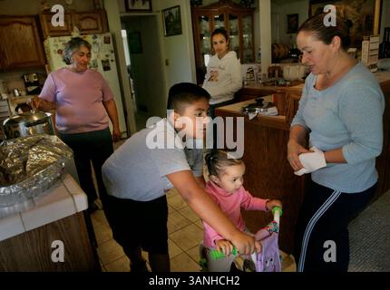 Jeudi 22 novembre 2007. NAPA, CA -. Luis Herrera emmène sa cousine Carolina dans la cuisine dans son vélo tandis que sa tante Lilia, à droite, et sa grand-mère Maria, préparent le dîner de Thanksgiving..Lianne Milton/Register (crédit image : © Napa Valley Register/ZUMApress.com) Banque D'Images