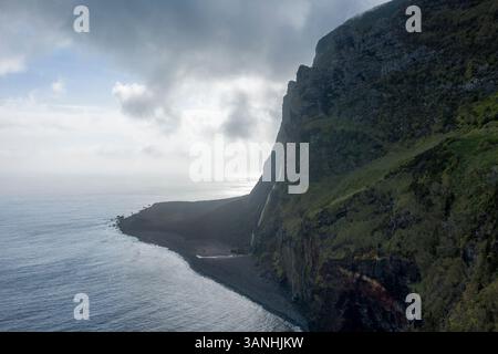 Vue aérienne d'une cascade le long de la côte au coucher du soleil, Ilha das Flores, îles des Açores, Portugal. Banque D'Images
