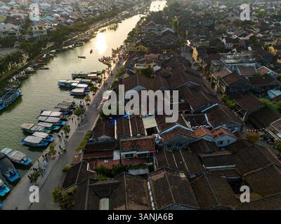 Vue aérienne de la belle architecture traditionnelle et charmants toits le long d'une rivière sereine au coucher du soleil, Minh an, Quang Nam, Vietnam. Banque D'Images