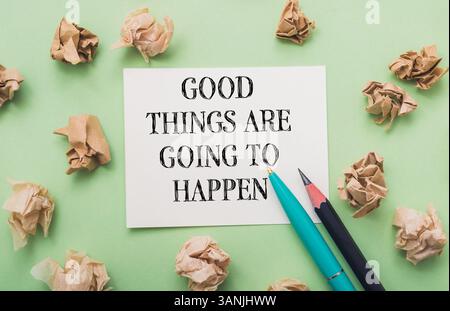 Morceau de papier avec les mots "de bonnes choses vont arriver" écrit dessus. Il y a aussi deux stylos sur le papier, dont l'un est bleu Banque D'Images