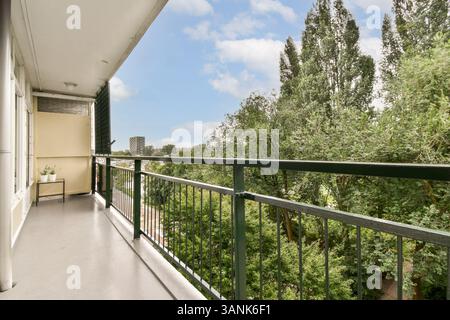 Un balcon serein surplombant une végétation luxuriante et des arbres, mettant en valeur une atmosphère paisible et un espace extérieur accueillant pour la détente. Banque D'Images