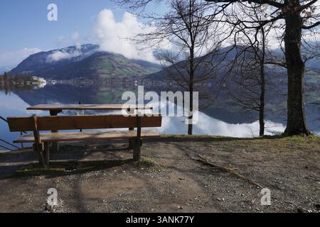 Le banc en bois et table avec vue, jour de temps nuageux de Zell am See, situé dans les Alpes autrichiennes. montagnes et ville sur fond, miroir sur Banque D'Images