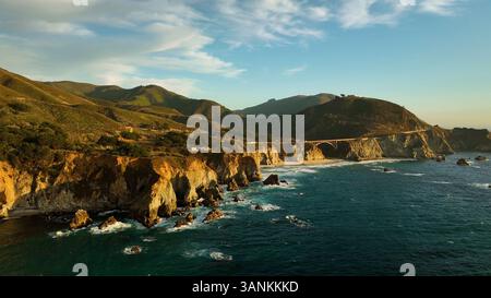 Vue aérienne du pont de bixby Creek au coucher du soleil avec des vagues et des nuages sur la côte, Big sur, Californie, États-Unis. Banque D'Images