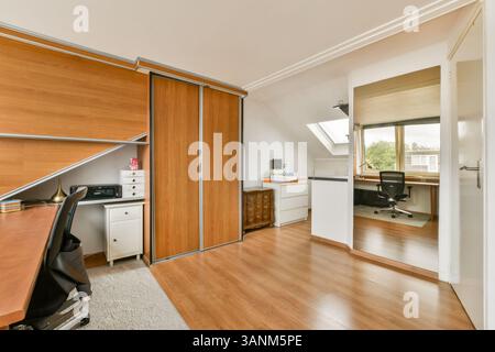 Un bureau à domicile moderne et élégant avec des meubles en bois, une grande fenêtre et un grand espace de rangement, créant un espace de travail fonctionnel et esthétique. Banque D'Images