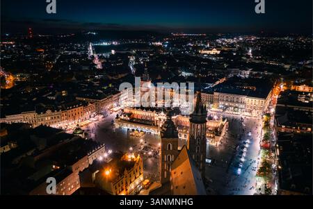 Vue aérienne de la place principale illuminée avec église Marie et Sukiennice, Cracovie, Pologne. Banque D'Images