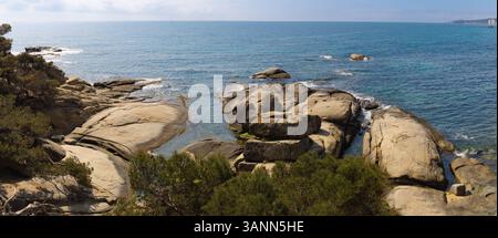 Vue panoramique à grand angle de Punta Rocas planes, Costa Brava, mettant en valeur les roches lisses uniques, la mer bleue et les pins au premier plan. Banque D'Images