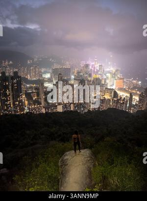 Vue aérienne d'un horizon à couper le souffle avec des gratte-ciel modernes et des lumières scintillantes au crépuscule, à l'est, Hong Kong. Banque D'Images