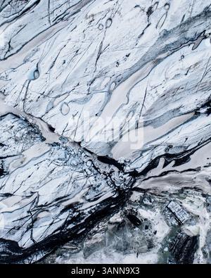 Vue aérienne du glacier Solheimajokull, et gros plan des motifs créés par la couche de cendres volcaniques noires entre la glace, au sud de l'Islande. Banque D'Images