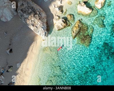Vue aérienne de la plage de mariolu avec une femme sur un matelas gonflable entouré d'eau turquoise et de côte rocheuse, Baunei, Italie. Banque D'Images