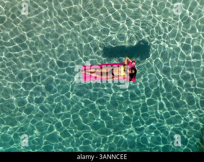 Vue aérienne de la plage de mariolu avec une femme sur un matelas gonflable dans une eau turquoise claire, Baunei, Italie. Banque D'Images