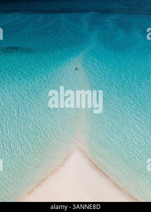 Vue aérienne d'une plage tropicale sereine avec une femme nageant dans l'eau cristalline, South Eleuthera, Bahamas. Banque D'Images