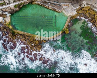 Vue aérienne d'une personne nageant à Bronte Baths, une piscine d'eau salée au bord de l'océan, Sydney, Nouvelle-Galles du Sud, Australie. Banque D'Images