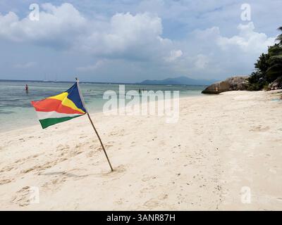 La Digue, Seychelles. 05 mars 2025. Un drapeau des Seychelles flotte sur la plage d'Anse source d'argent. On dit que la plage est l'une des plus belles plages des Seychelles. L'île est en grande partie sans voiture. La Digue est la plus petite des trois îles principales habitées des Seychelles. Crédit : Alexandra Schuler/dpa/Alamy Live News Banque D'Images