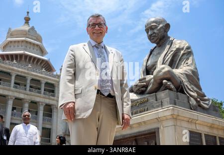 Neu Delhi, Inde. 15 avril 2025. Florian Herrmann (CSU), chef de la Chancellerie d’État bavaroise, se tient devant une statue surdimensionnée du Mahatma Gandhi lors d’un voyage en Inde de plusieurs jours du premier ministre bavarois Söder. Le premier ministre bavarois Söder ne peut pas participer au reste du voyage après être tombé malade et est remplacé par Herrman. Crédit : Peter Kneffel/dpa/Alamy Live News Banque D'Images