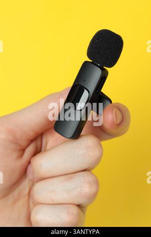 Femme tenant le micro-cravate sur fond jaune, gros plan Banque D'Images