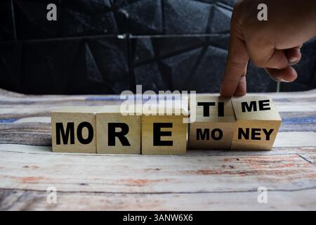 Concept Word plus de temps ou plus d'argent, main flip cubes et change l'inscription plus d'argent à plus de temps sur des blocs de bois sur une table en bois Banque D'Images