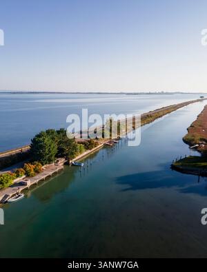 Vue aérienne des véhicules roulant sur une belle route traversant le lagon à Grado près de Gorizia, Friuli Venezia Giulia, Italie. Banque D'Images