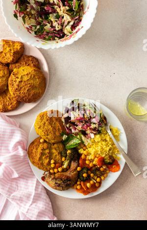 Un petit déjeuner copieux et équilibré avec des crêpes aux lentilles et aux courgettes, du millet, du cou de poulet cuit au four, des patates douces rôties, du brocoli, des carottes, des pois chiches et une salade fraîche avec des radis, des pousses et des noix Banque D'Images