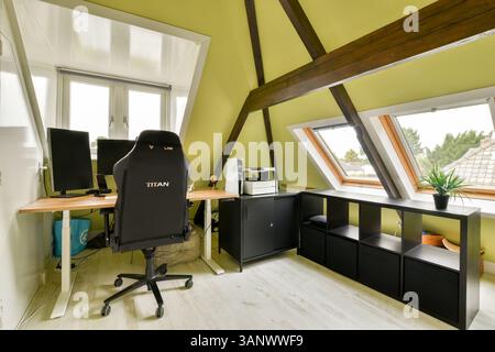 Un élégant espace de bureau à domicile avec une chaise confortable, un bureau et de grandes fenêtres pour une lumière naturelle abondante, créant un environnement de travail inspirant. Banque D'Images