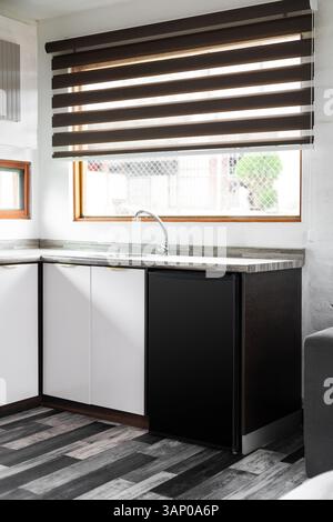 Une superbe cuisine moderne au design élégant, avec de grandes fenêtres qui s'ouvrent sur une vue sereine sur le jardin, créant une atmosphère lumineuse et accueillante. Banque D'Images