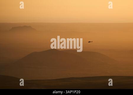 Vue aérienne d'un hélicoptère volant bas dans la brume avec un beau paysage en arrière-plan au coucher du soleil, Grindavík, péninsule sud, Islande. Banque D'Images