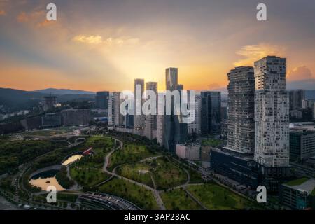 Vue aérienne par drone du parc la Mexicana à Santa Fe, un quartier financier de Mexico, avec des gratte-ciel au coucher du soleil, Mexique. Banque D'Images