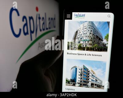 Stuttgart, Allemagne - 12-04-2024 : personne tenant un téléphone portable avec la page web de la société CapitaLand Integrated commercial Trust (CICT) sur l'écran avec le logo. Banque D'Images