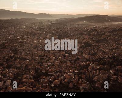 Vue aérienne de beau paysage urbain avec des bâtiments historiques et des montagnes au coucher du soleil, Stari Grad, Sarajevo, Bosnie-Herzégovine. Banque D'Images
