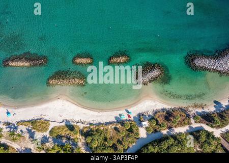 Vue aérienne des barrières rocheuses sur le rivage dans les eaux bleues claires, le sable blanc et les gens sur la plage de Peanut Island Park, Floride, États-Unis Banque D'Images