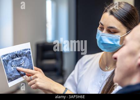 Jeune dentiste montrant une radiographie dentaire à un patient. Concept de dentisterie. Banque D'Images
