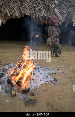 Portrait d'un garçon devant un temple, vêtu d'un costume rituel fait de peaux d'animaux et de plumes, un matin après une cérémonie toute la nuit. Banque D'Images