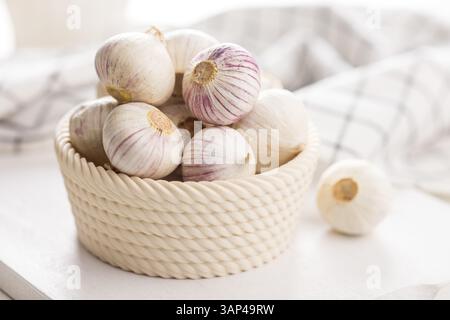 Bulbes d'ail gant solo dans un bol sur une table blanche. Banque D'Images