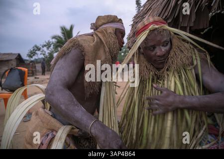 Participants à une cérémonie Bwiti, vêtus d'une tenue rituelle faite de feuilles de palmier séchées, après une séance toute la nuit. Banque D'Images