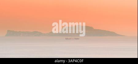 Vue aérienne du coucher de soleil panoramique sur l'île de Capri avec mer sereine et silhouette d'un navire, Naples, Italie. Banque D'Images
