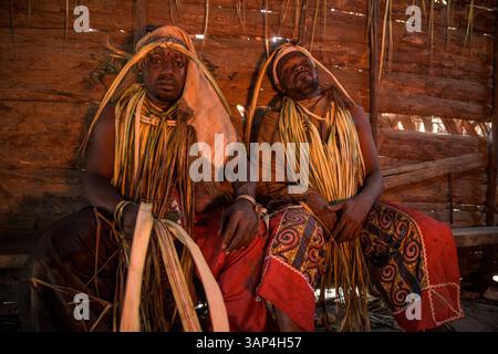 Participants à une cérémonie Bwiti, vêtus d'une tenue rituelle faite de feuilles de palmier séchées, après une séance toute la nuit. Banque D'Images