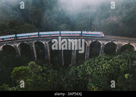 Vue aérienne du train bleu passant par le célèbre pont ferroviaire Nine Arch debout dans un paysage de jungle verdoyant près d'Ella, Sri Lanka. Banque D'Images