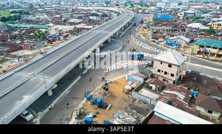 Vue aérienne de la construction de passages supérieurs dans un paysage urbain animé avec des bâtiments et des véhicules, Rumuokwuta, Nigeria. Banque D'Images
