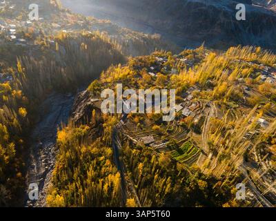 Vue aérienne du village pittoresque niché dans des montagnes majestueuses et des forêts luxuriantes, Hunza Valley, Pakistan. Banque D'Images